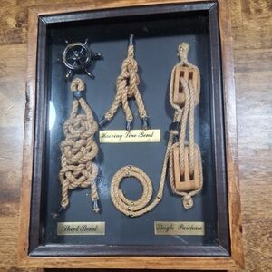 Decorative shadow box featuring various nautical knots and a ship's wheel.